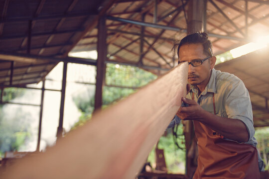 Carpenter holding a piece of wood in a workshop