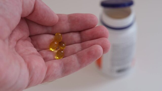 A man holding vitamin D3 capsules in his hand. Close up.