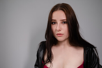 Fototapeta premium young brunette woman in black leather jacket. beautiful girl millenial on grey background.
