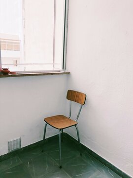 Chair in the corner of a room by a window with two ashtrays on a window sill