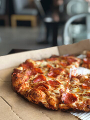 pepperoni pizza in open box, with blurred restaurant background and copy space