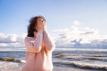 The brunette covers her face with her hands. A girl in a deep depression. The woman has a tragedy. The girl enjoys the sea and breathes deeply.