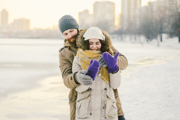 Young couple cheerfully flounders in snow. Between comic fight. Happy young couple hugs in winter...