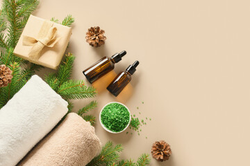 Obraz na płótnie Canvas Christmas Spa concept with cosmetic aroma oil, pine cones, evergreen branches on beige background. Winter holiday for body care and wellness. View from above. Special offer for beauty saloon.