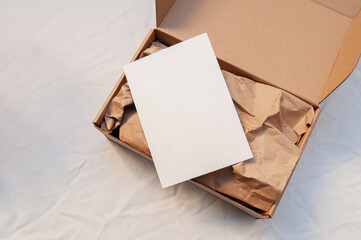 Overhead view of a blank envelope on an open cardboard box