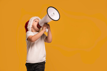 Child boy in Santa hat holding megaphone in hand , screaming some news