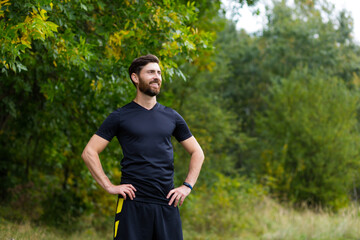 Close up portrait young happy bearded man standing in nature between forest trees relaxes, breathes fresh air closing his eyes. Male enjoys a life of peace calm, quiet in the park. Outdoors. Happiness