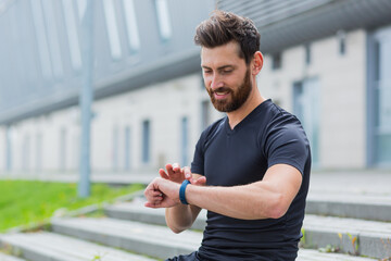 Sport Caucasian man looking smart watch at modern track runner using use smartwatch fitness bracelet Portrait fit male athlete checking result jogging in sportswear in street urban city park outdoor