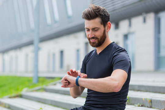 Sport Caucasian man looking smart watch at modern track runner using use smartwatch fitness bracelet Portrait fit male athlete checking result jogging in sportswear in street urban city park outdoor - Powered by Adobe