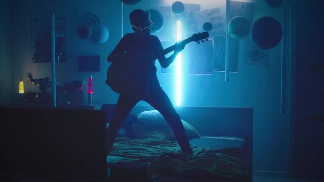 Cool teenager playing guitar in bedroom