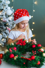 Santa little helper with decorative christmas tree on background. Little smiling girl make...