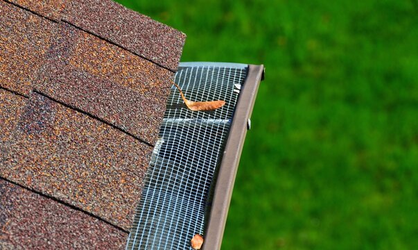Closeup of a metal filter on a gutter. A leaf on the filter. House maintenance
