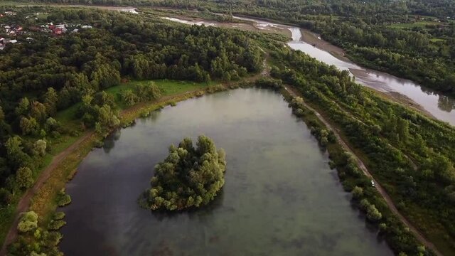 View of the Shevchenko lake in the park in Kolomyia. The Prut river in the distance. Island with trees and water. Drone Video. Ukraine. Europe