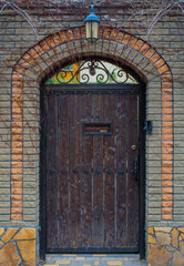 Photo of old brown gateway with stone arch and lantern