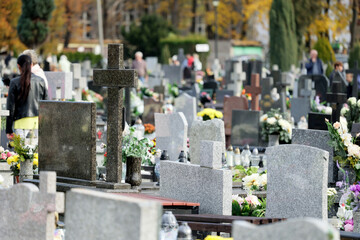 Szereg grobów na cmentarzu  w czasie święta zmarłych.