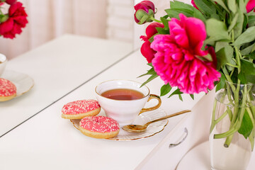 Client place in hairdressing beauty salon with cup of tea, donuts and peonies flowers
