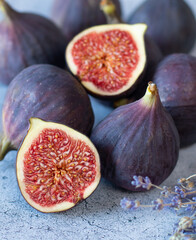 Fig fruits, whole and halves, and a branch of lavender on a gray background