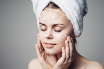 woman with bare shoulders towel on head face cream skin care