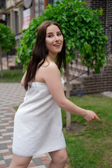 confident brunette woman in white towel running by the street. crazy beautiful millennial carefree girl.
