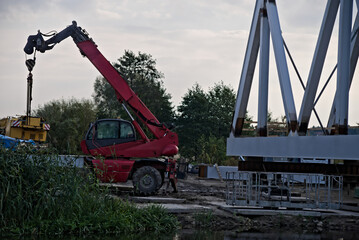 Budowa mostu . Czerwona koparka , dźwig i most. Building a bridge.. Red excavator, crane and bridge  - obrazy, fototapety, plakaty