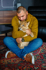 Man playing with a young lion cub in the room