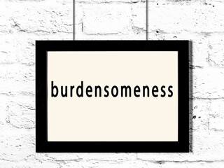 Black frame hanging on white brick wall with inscription burdensomeness