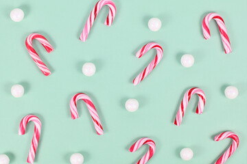 Small red and white striped Christmas candy cane sweets on mint green background