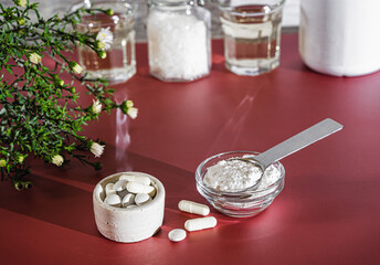 Biological supplement collagen in the form of powder, tablets and capsules in small cups against...