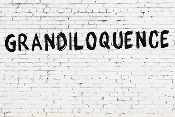 Inscription grandiloquence painted on white brick wall