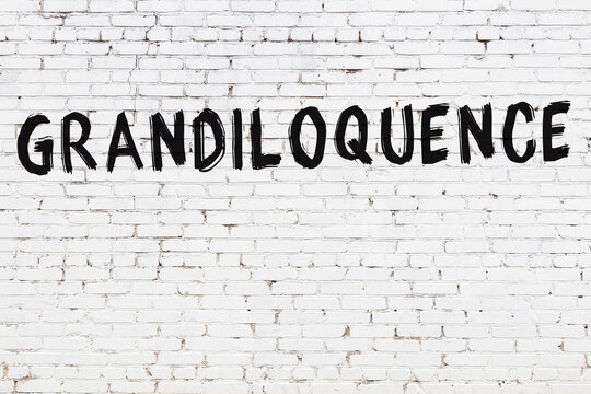 Inscription grandiloquence painted on white brick wall