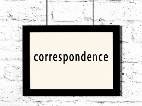 Black frame hanging on white brick wall with inscription correspondence