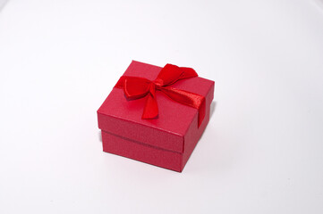 Closed red box with a red ribbon for a ring on a white background