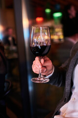 A man holds a glass of red wine in his hand.
