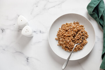 boiled buckwheat porridge with a spoon on a marble table with green napkin