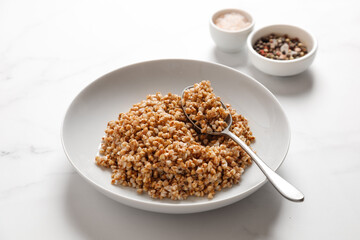 boiled buckwheat porridge with a spoon on a marble table