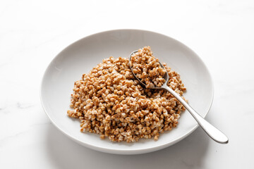 boiled buckwheat porridge with a spoon on a marble table