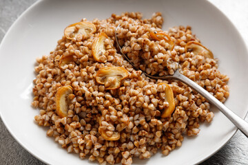 boiled buckwheat porridge with mushrooms with a spoon on the plate