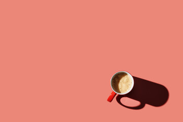 Top view of a cup of coffee on orange pastel background