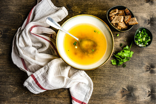 Bowl of healthy chicken broth with croutons, parsley and spring onions