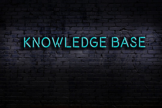 Neon sign. Word knowledge base against brick wall. Night view