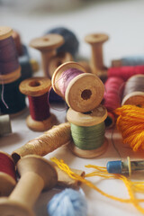 Sewing tools, vintage wooden bobbins with colorful thread on white table
