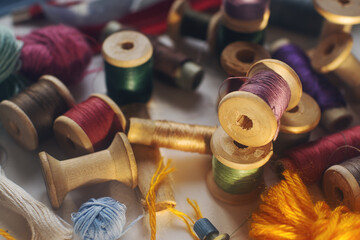 Sewing tools, vintage wooden bobbins with colorful thread on white table