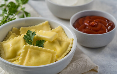 Macro photography. A serving of delicious ravioli with a lump of butter and a parsley leaf and two sauces. White background. There are no people in the photo. Advertising, restaurant.