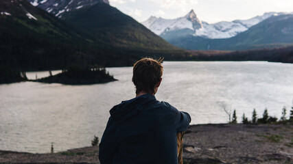 man sitting surrounded by mountains and a beautiful lake
