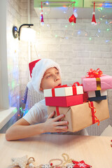 The child holds heavy boxes with gifts.Christmas gifts with your own hands. Home leisure with children in the New Year.