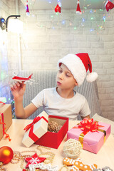 A child in a Santa Claus hat is playing with a plane that he received for Christmas. Christmas interior of the house.