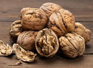 pile of inshell walnuts on a brown wooden table, autumn harvest