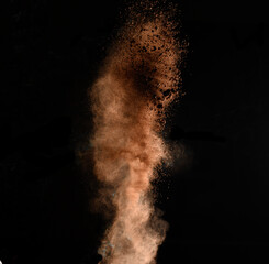 flying brown cocoa particles on a black background. Powder flies up