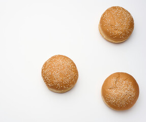 baked round fresh white wheat flour bun sprinkled with sesame seeds on a white table. Hamburger, cheeseberger and sandwich bun