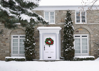 Front of traditional house with brightly decorated Christmas wreath on front door